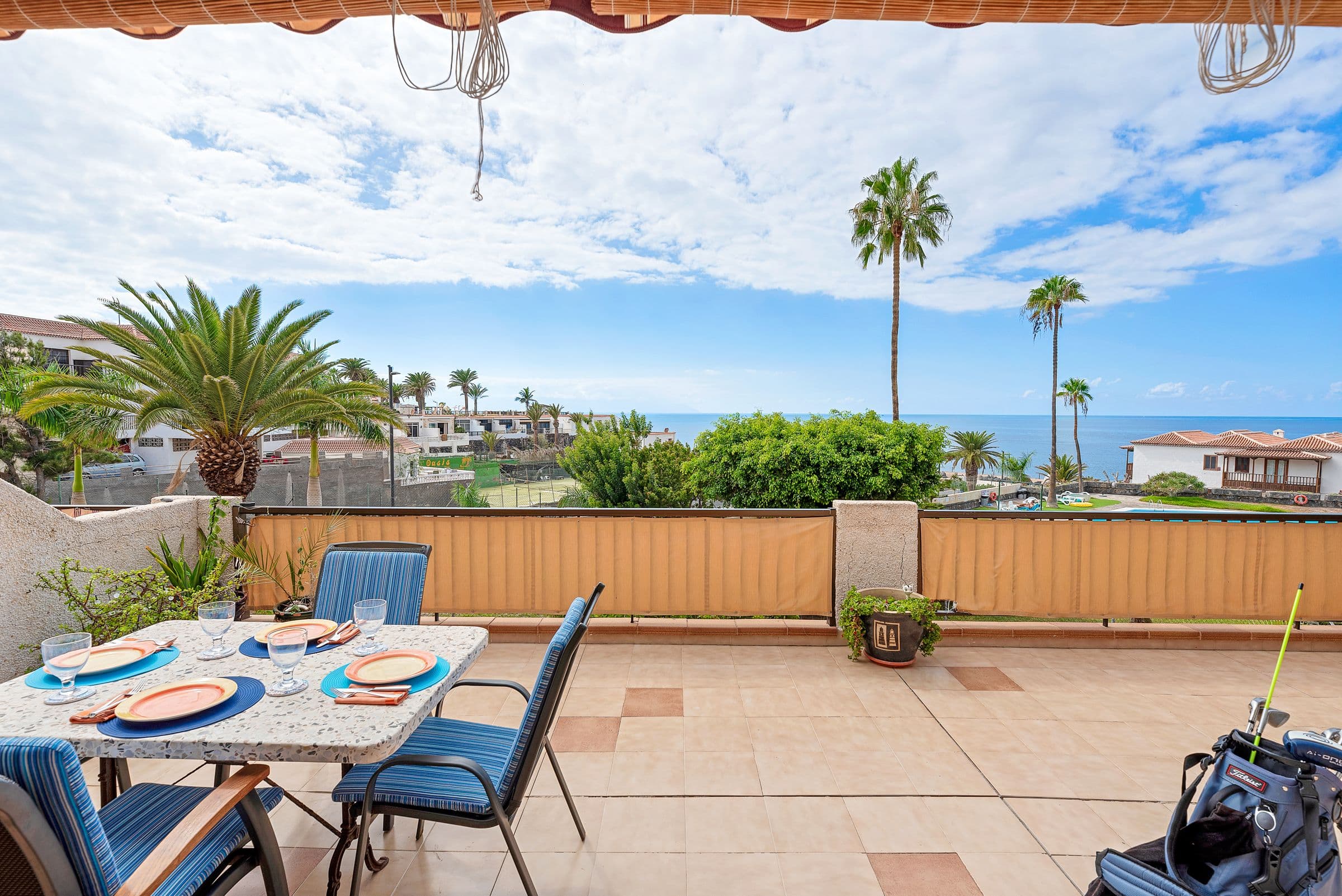 Terrace with dining table, palms and sea view